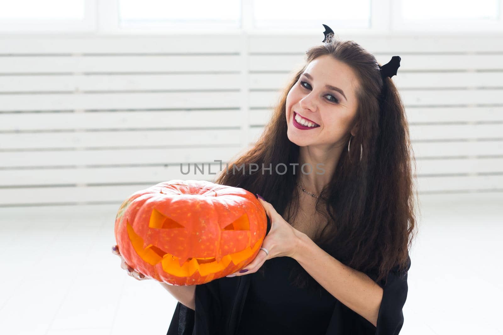 Halloween concept - Happy witch with pumpkin Jack-o'-lantern.