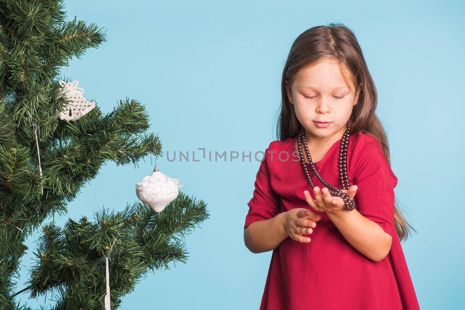 Little girl with christmas tree on blue background.