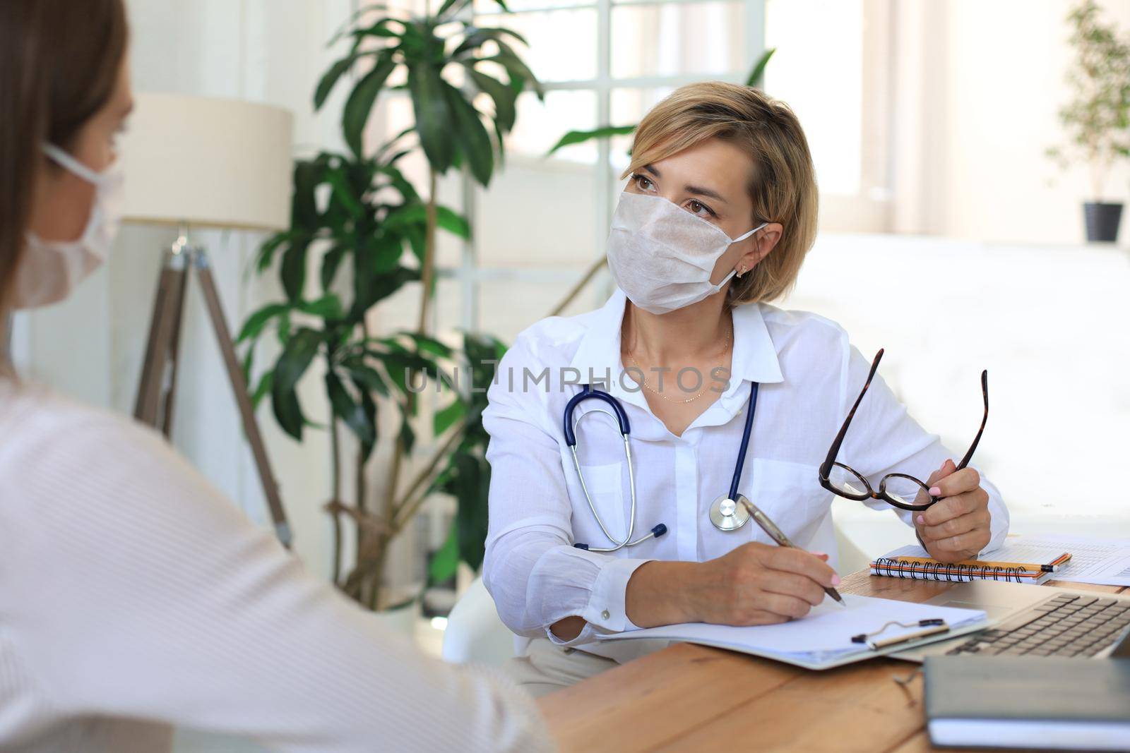 Middle aged female doctor therapist in consultation with patient in office