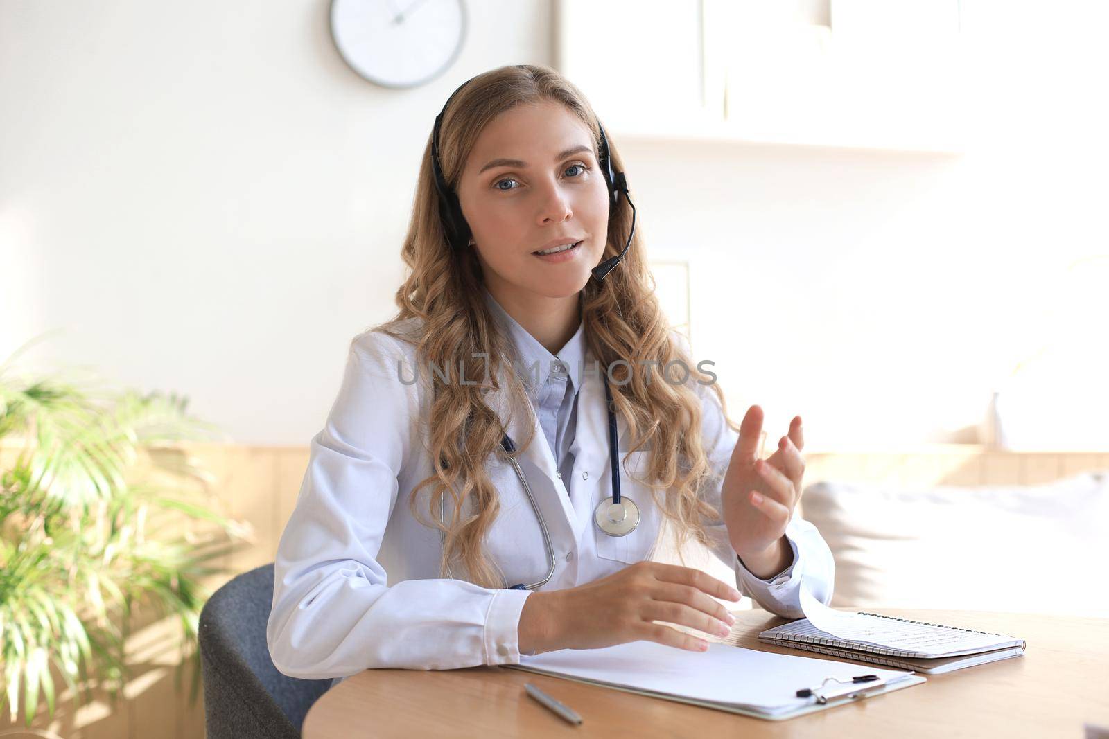 Smiling attractive female doctor talking at camera with patient