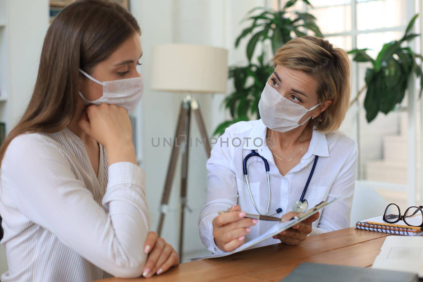 Middle aged female doctor therapist in consultation with patient in office