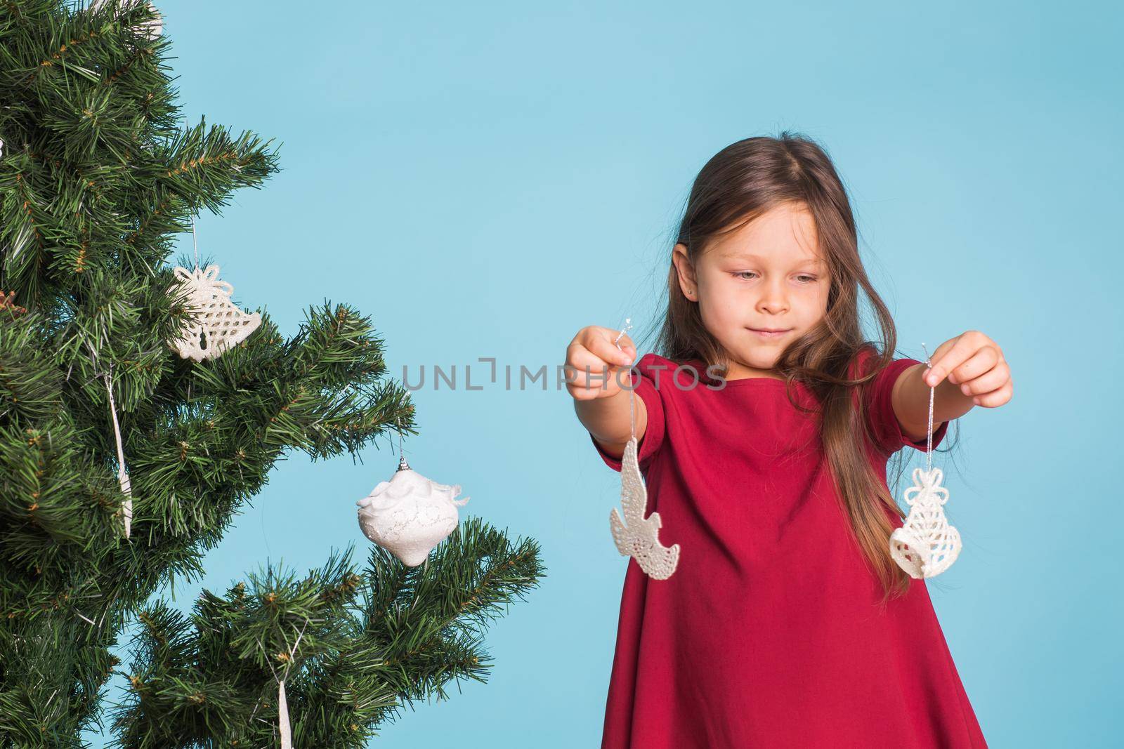 Christmas, childhood and people concept - little girl decorating the christmas tree.