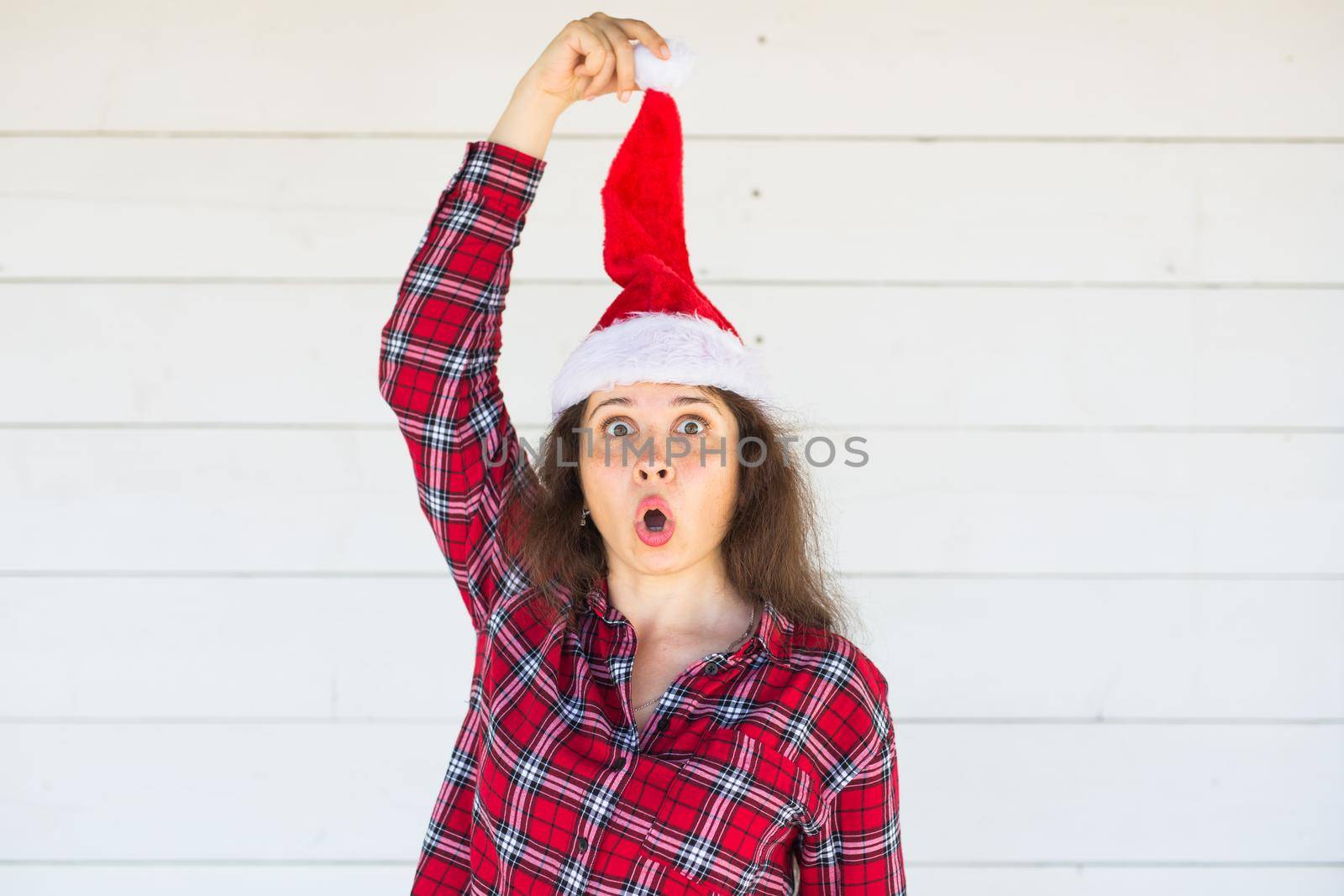 Holidays, christmas and clothing concept - funny woman in santa hat posing on white background by Satura86