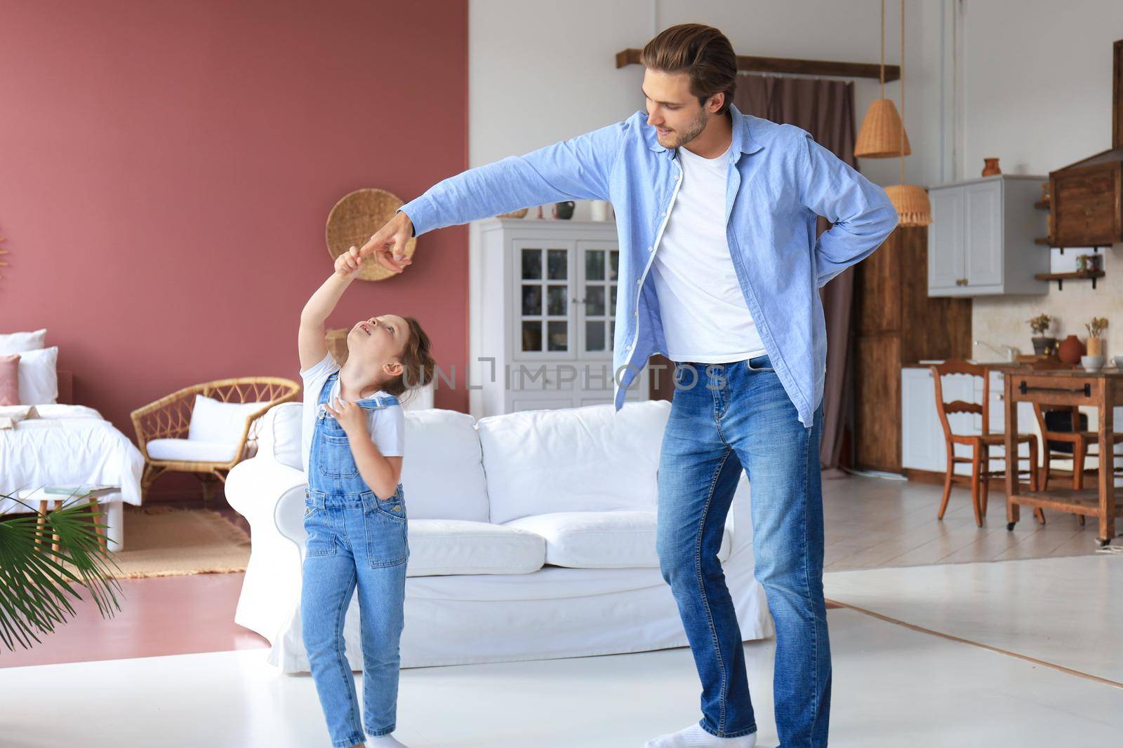 Handsome young man dancing at home with his little cute daugther