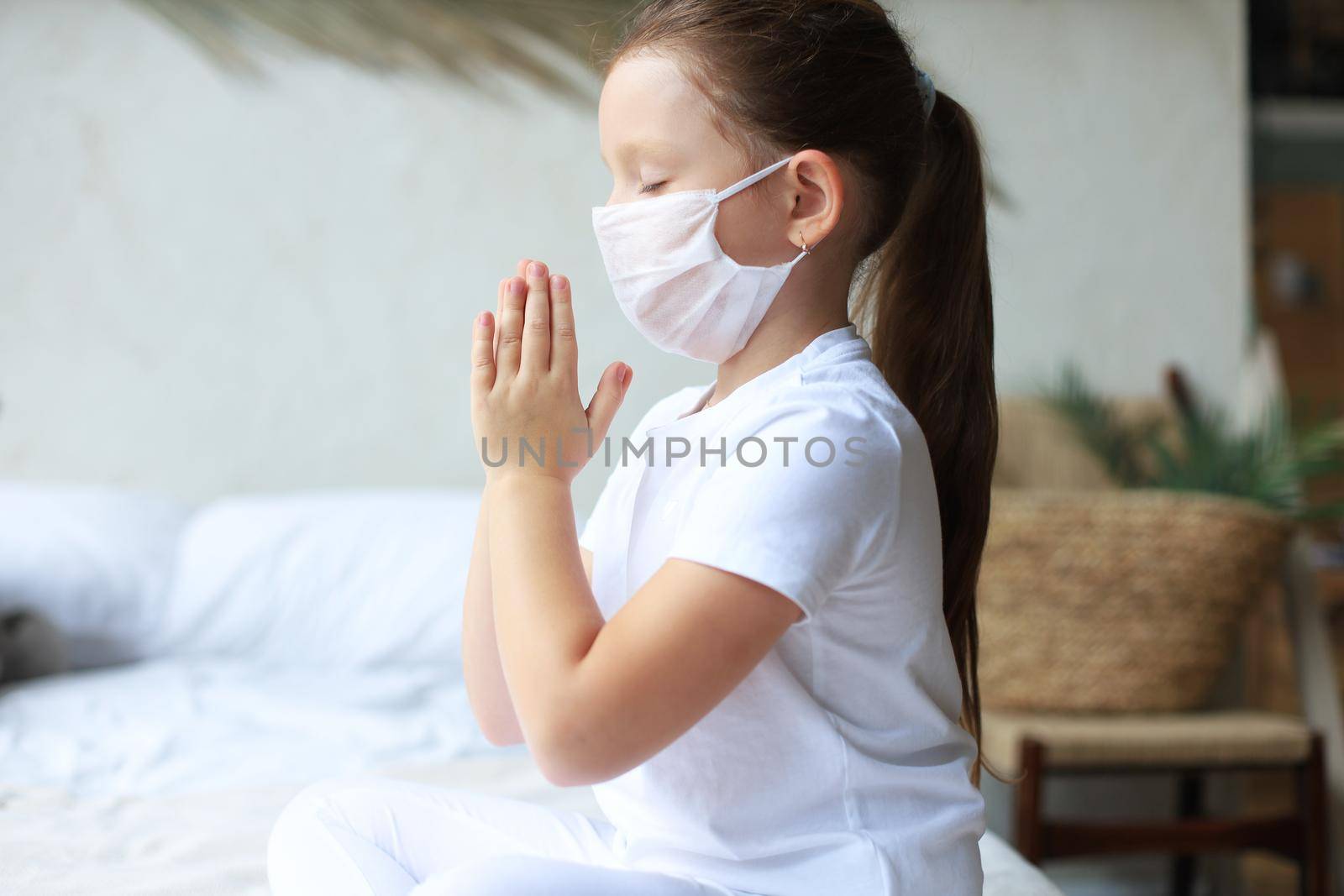 Little girl wearing mask for protect Covid-19. She praying in the morning for a new day freedom to world corona virus. Little girl hand praying for thank GOD.