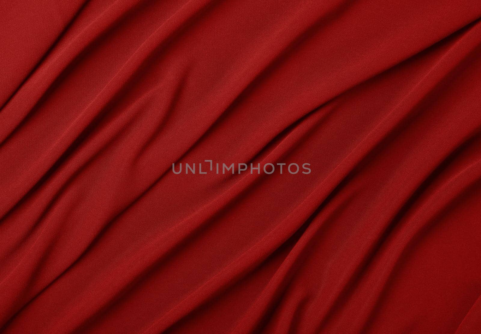 Close up abstract textile background of red folded pleats of fabric, elevated top view, directly above