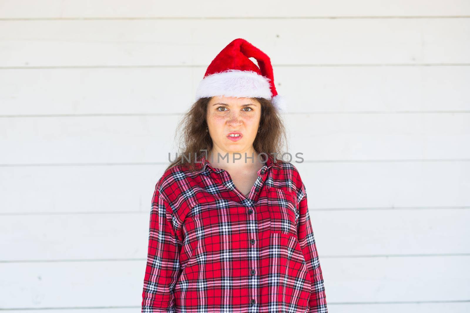 Christmas, people, emotions concept - dissatisfied angry santa in christmas hat .