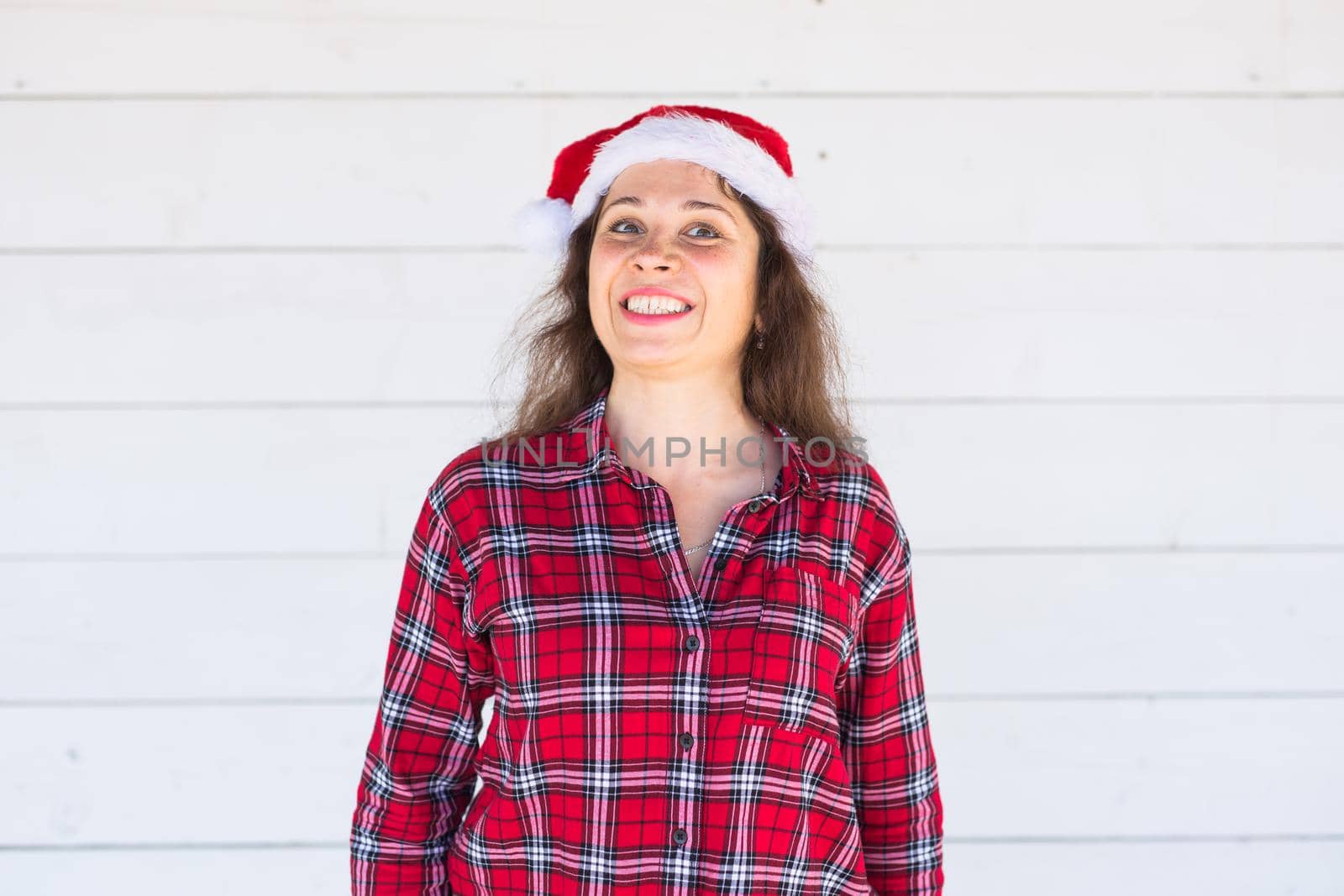 Christmas, holidays, people concept - young woman in santa hat and shirt smiling over the white background.