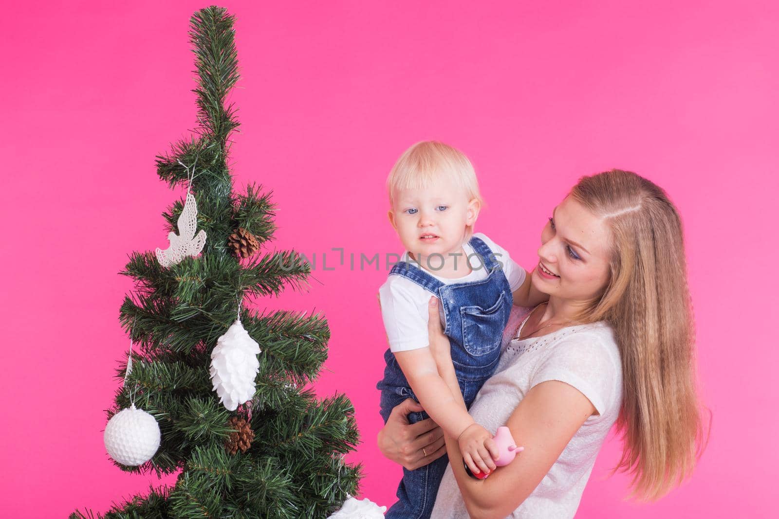 Christmas and holiday concept - Portrait of smiling woman with her little daughter decorating Christmas tree.
