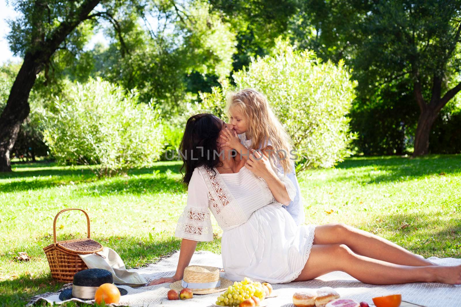 young pretty pregnant brunette woman having fun with her daughter on picnic on green grass in park, lifestyle people concept by JordanJ