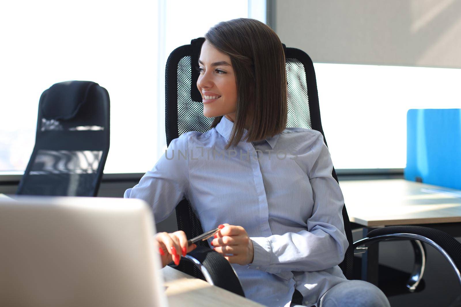 Smiling modern woman is thinking about business while working in the office