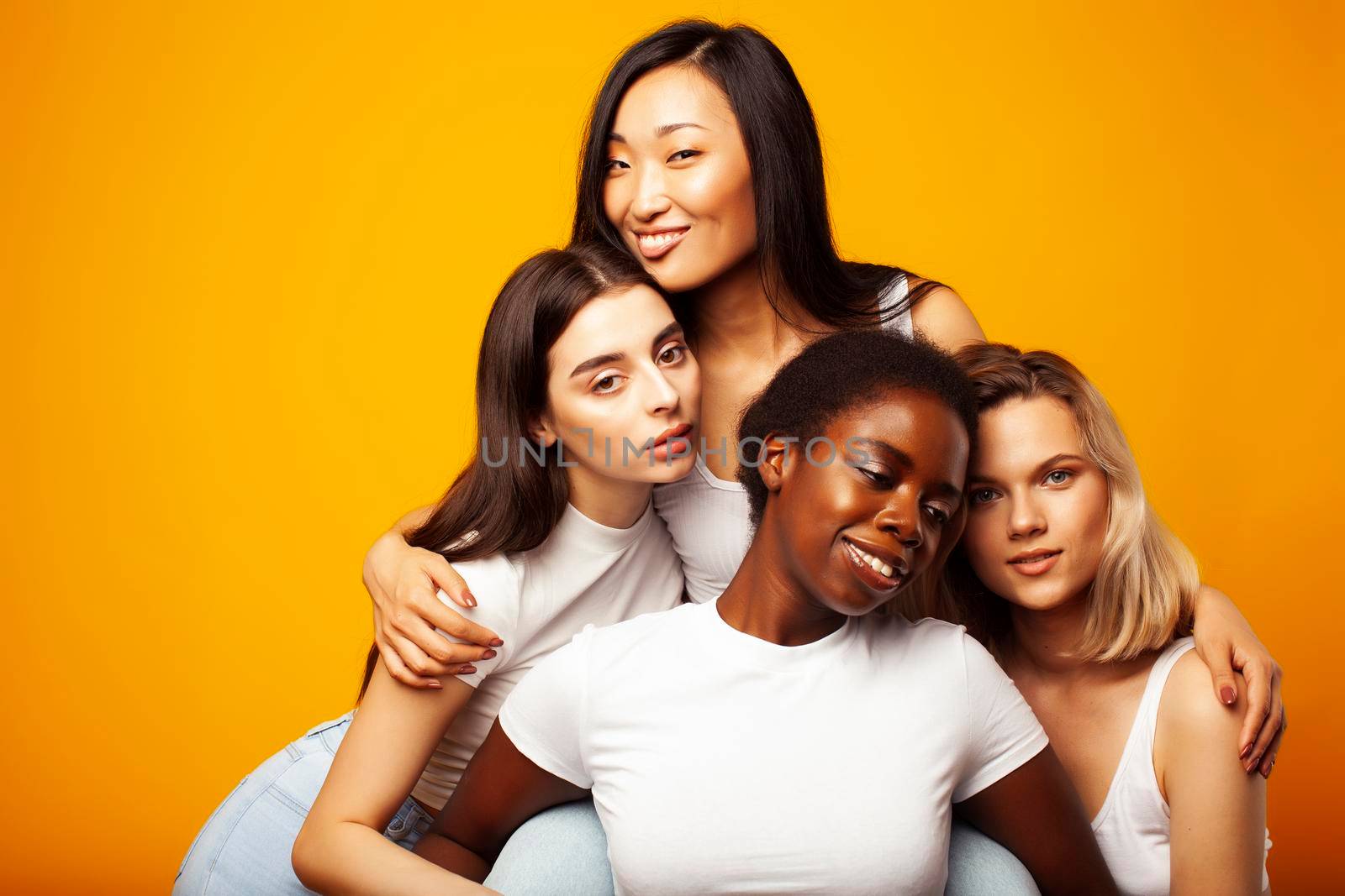 diverse multi nation girls group, teenage friends company cheerful having fun, happy smiling, cute posing on yellow background, lifestyle people concept, african-american, asian and caucasian close up