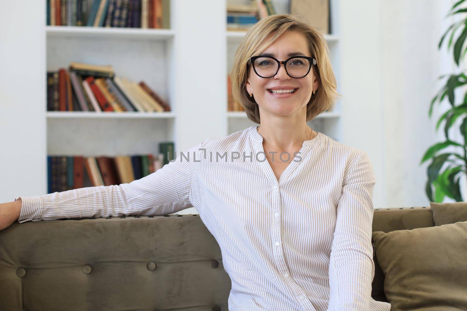Beautiful blond middle aged woman relaxing sitting on sofa