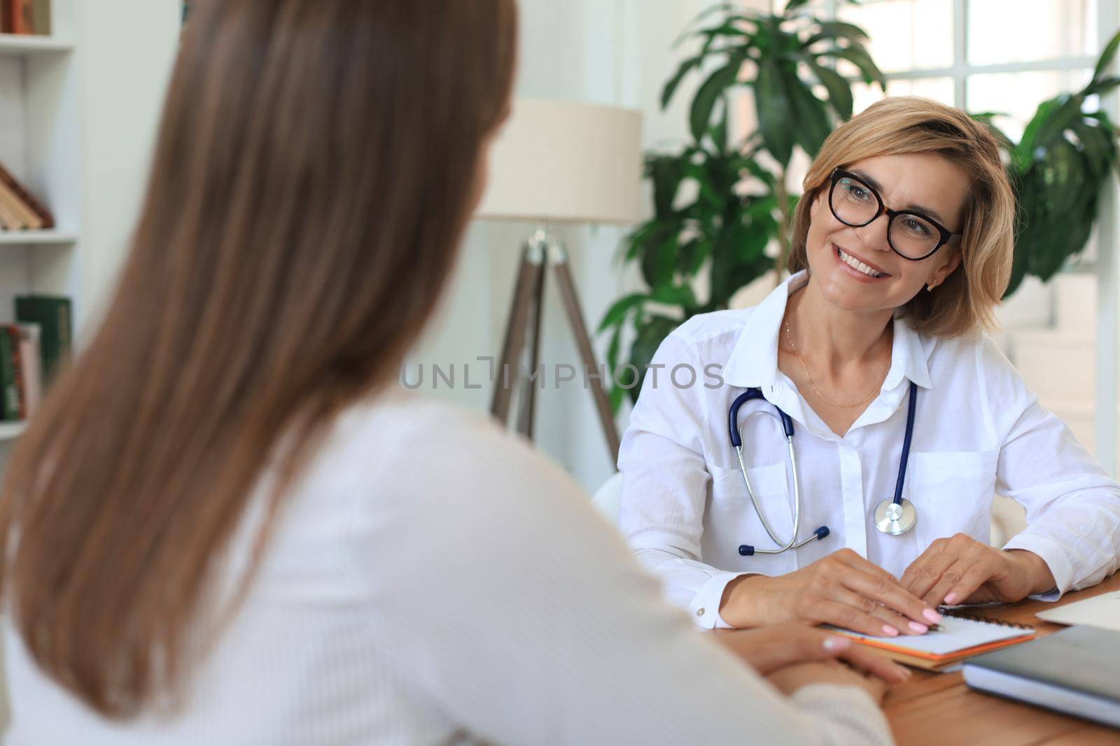 Middle aged female doctor therapist in consultation with patient in office