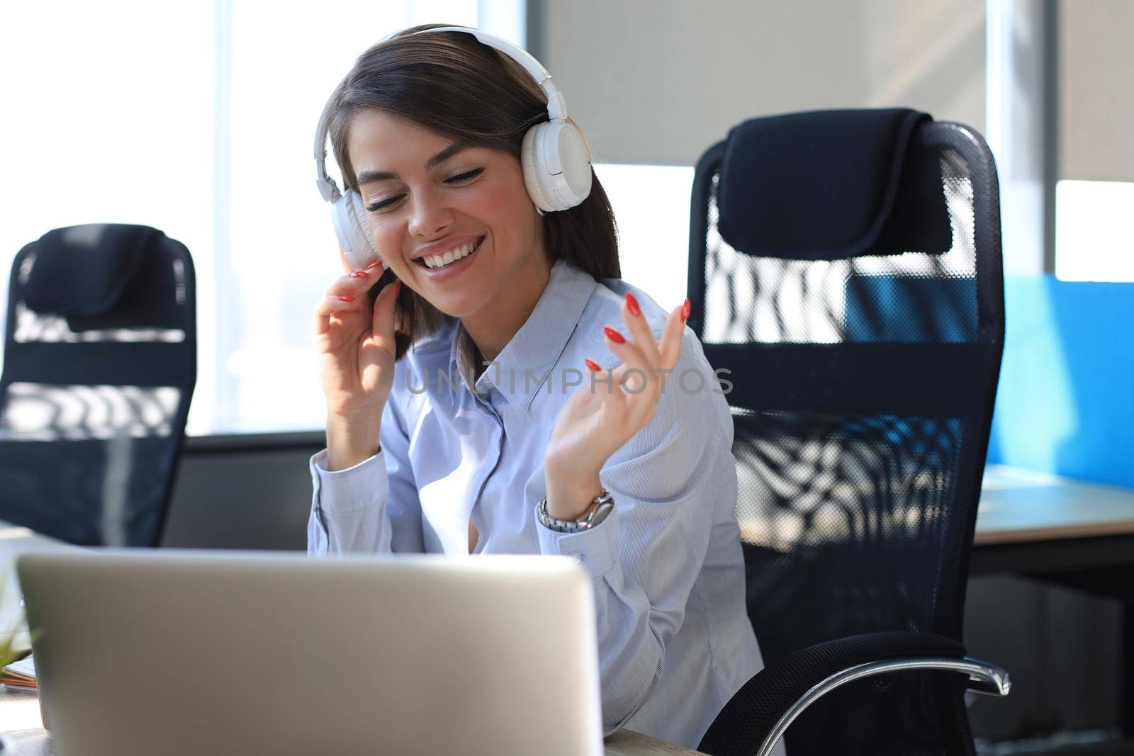 Portrait of beautiful young woman working on computer and chatting sitting in earphones
