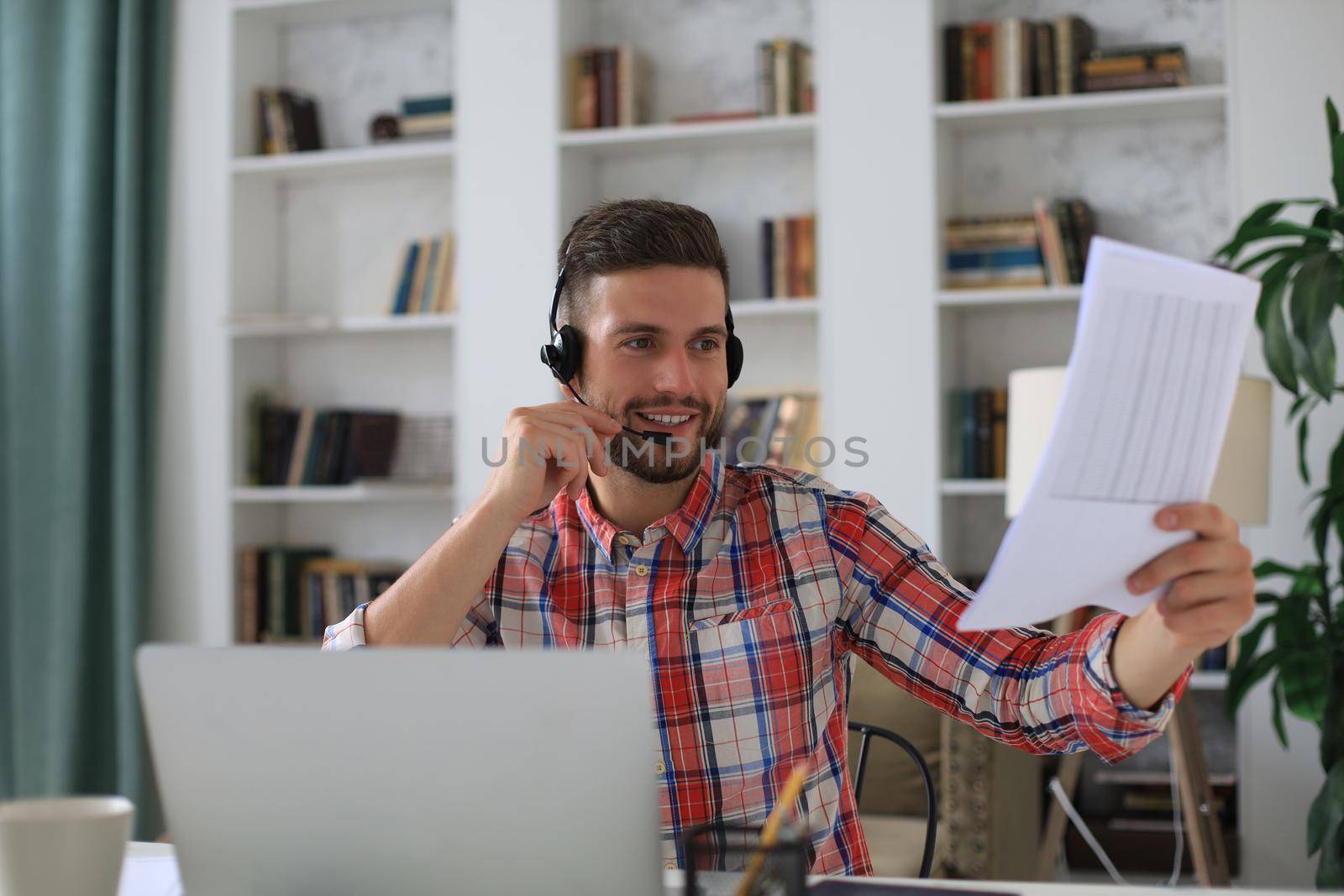 Concentrated young freelancer businessman using laptop for video conferance, working remotely online at home