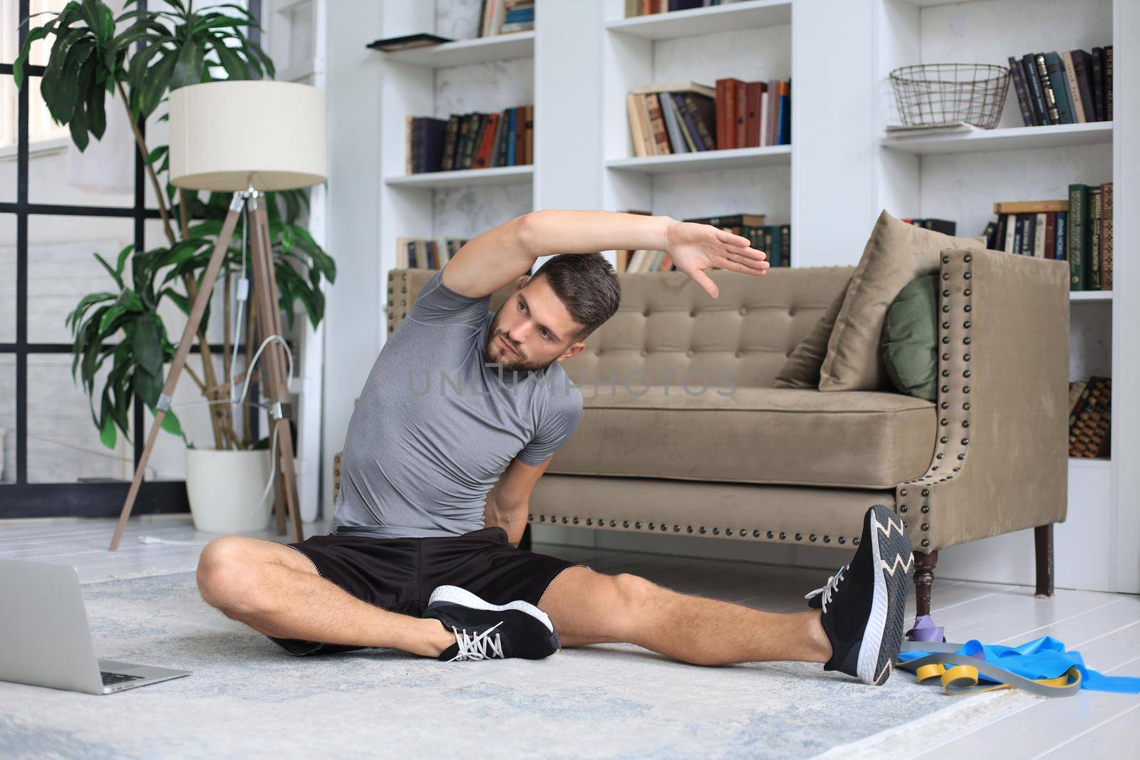 Handsome man doing stretching exercise at home during quarantine. Concept of healthy life