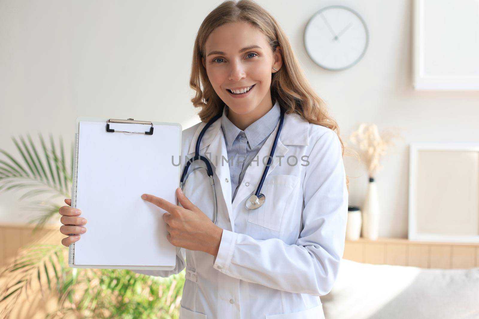 Young beautiful female doctor in white coat with phonendoscope. Doctor make video call interact through internet talk with patient provide help online counseling