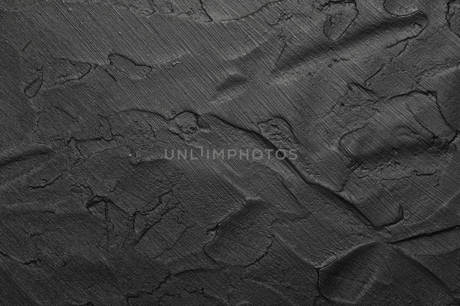 Black abstract background texture of uneven grunge surface with brushstrokes of plaster and paint