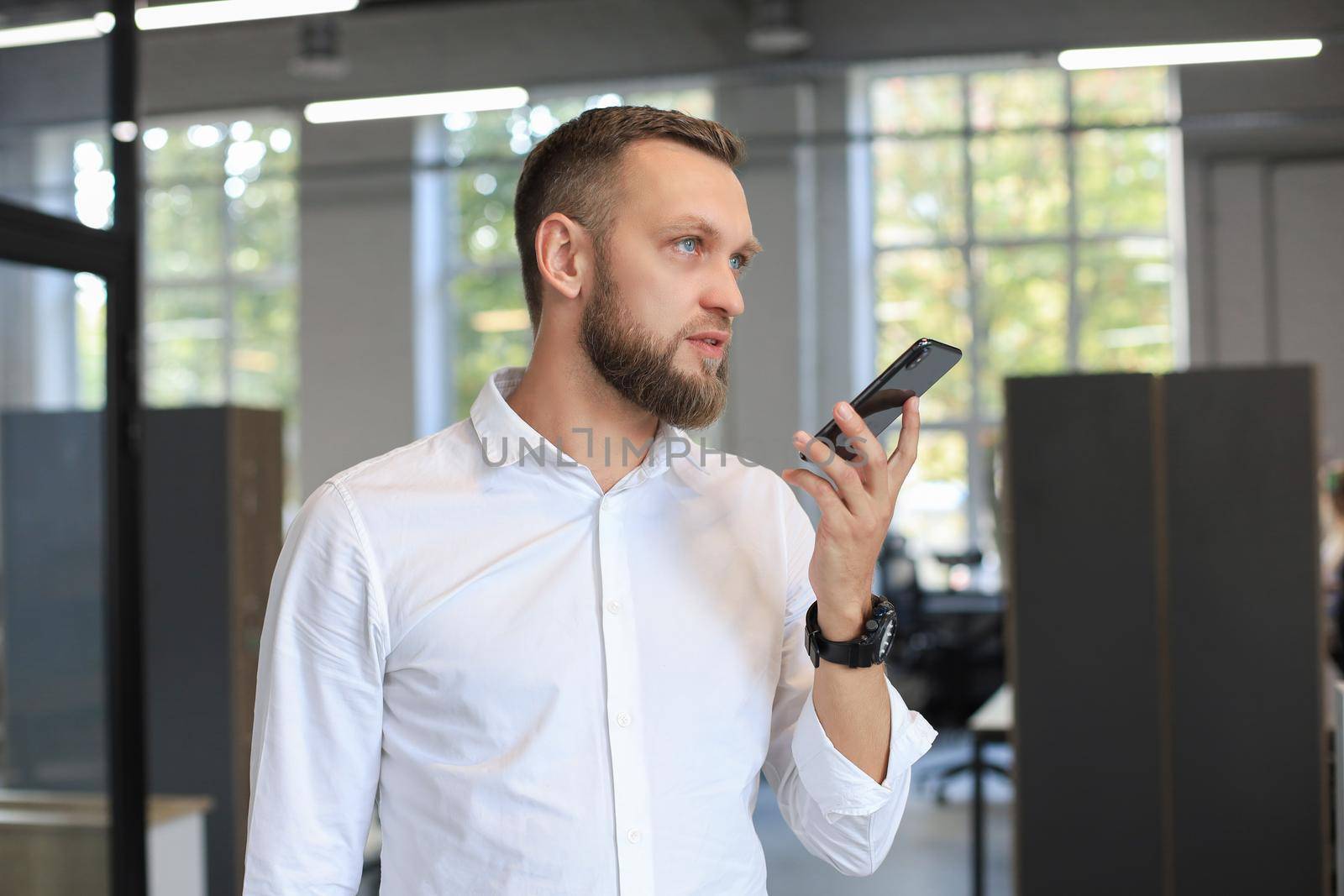 Handsome business man using a voice recognition app in office