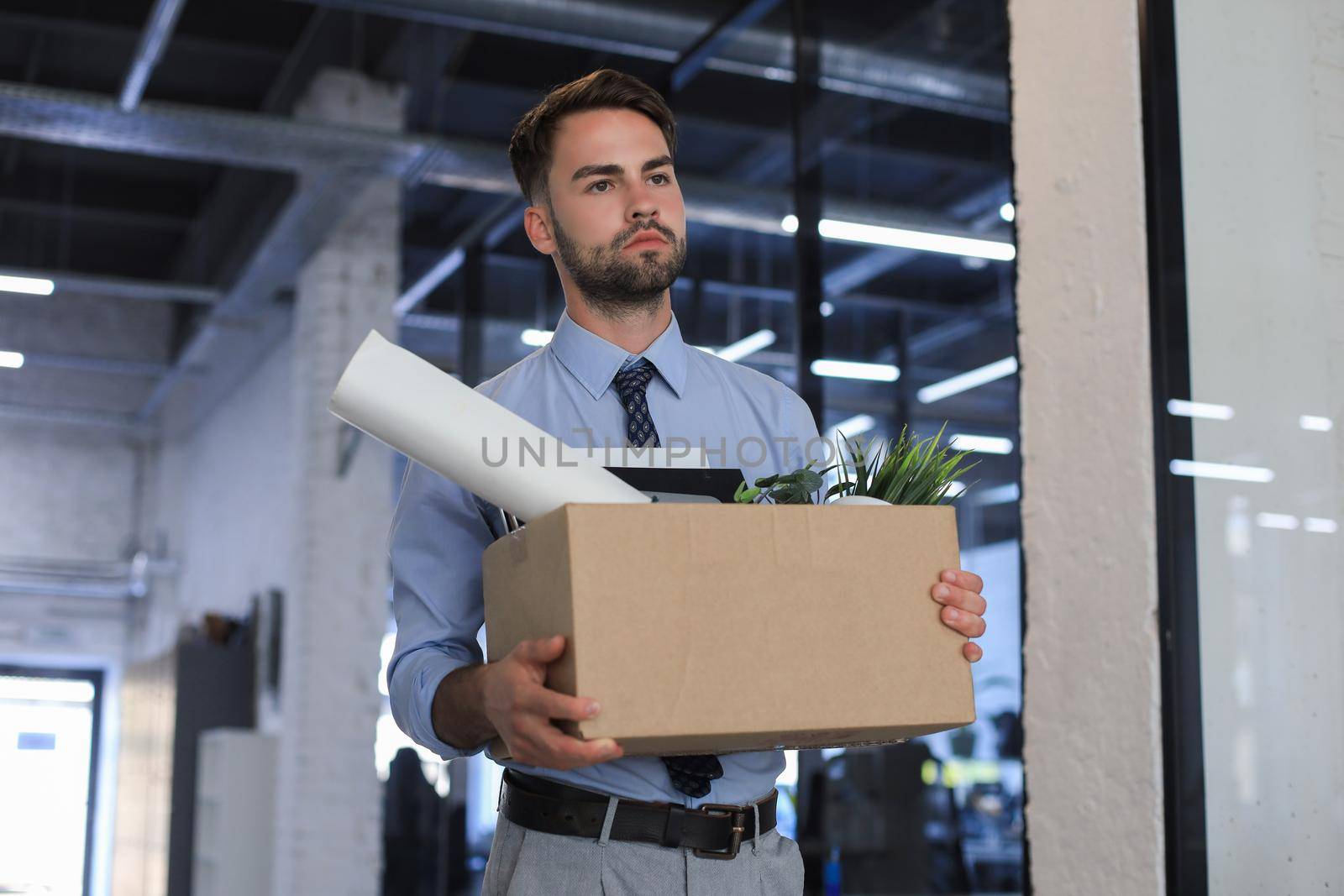 Sad dismissed worker is taking his office supplies with him from office