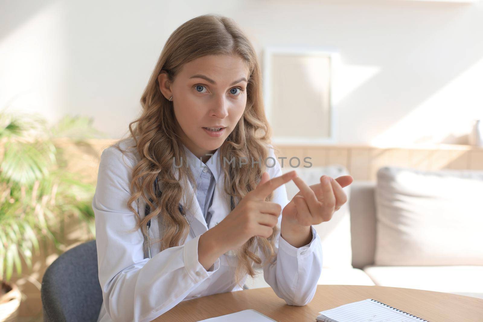 Smiling attractive female doctor talking at camera with patient
