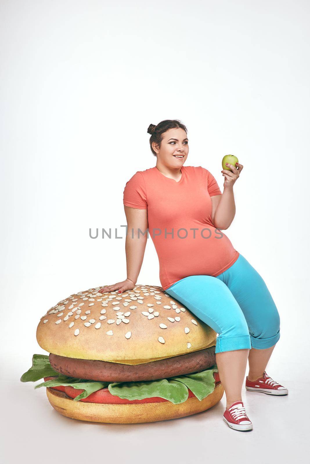 Brunette, funny, plump woman sits on a huge sandwich by friendsstock