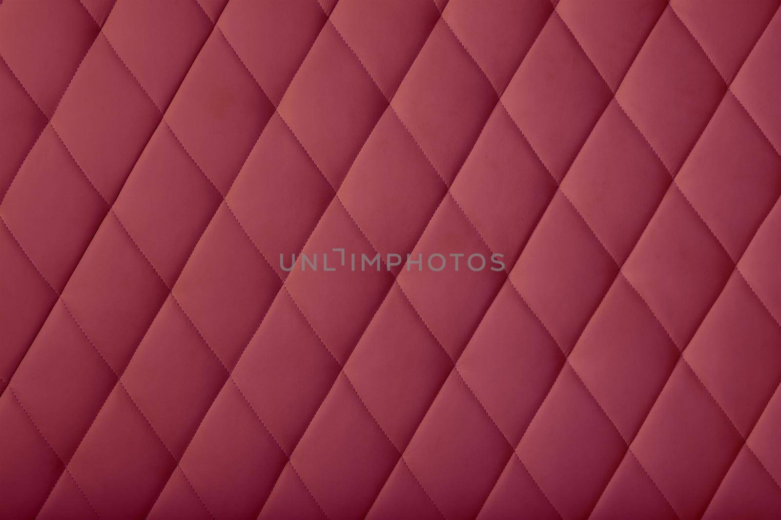 Background texture of burgundy purple soft tufted furniture or wall panel upholstery with deep diamond pattern, close up