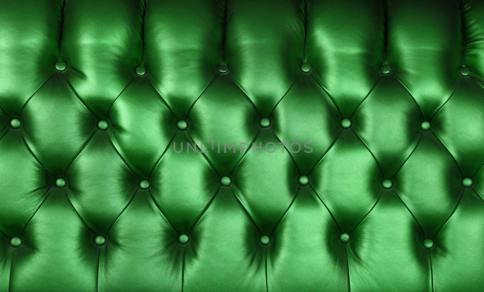 Background texture of dark emerald green capitone genuine leather, retro Chesterfield style soft tufted furniture upholstery with deep diamond pattern and buttons, close up