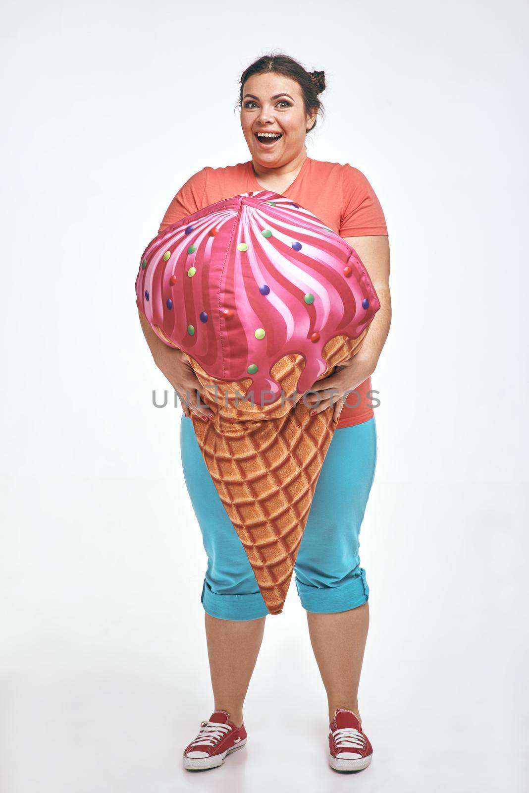 Brunette, chubby woman is holding a huge ice cream by friendsstock