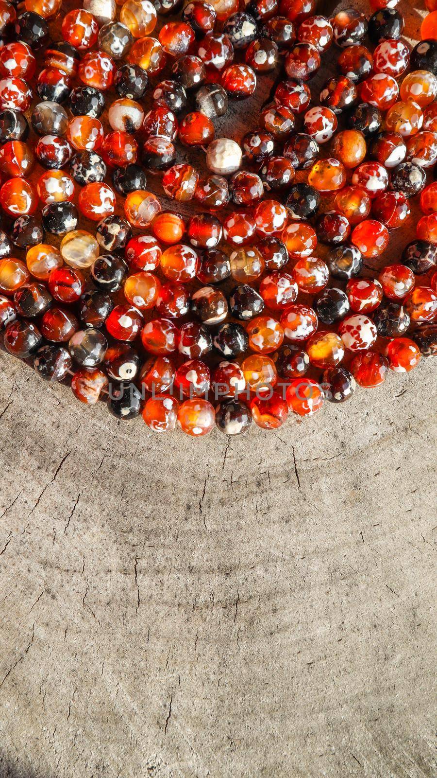 Beads of amber fireplace faceted agate on rough surface of an old stump. Vertical image 16x9 by Olayola