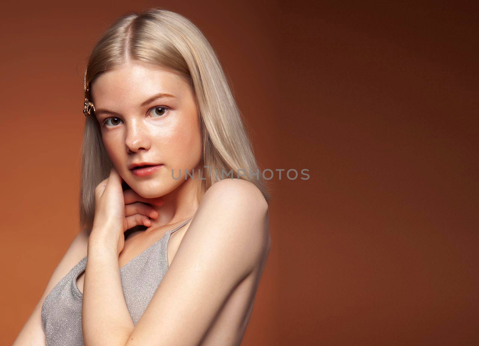 young pretty girl with blond hair posing cheerful on brown background, lifestyle people concept close up