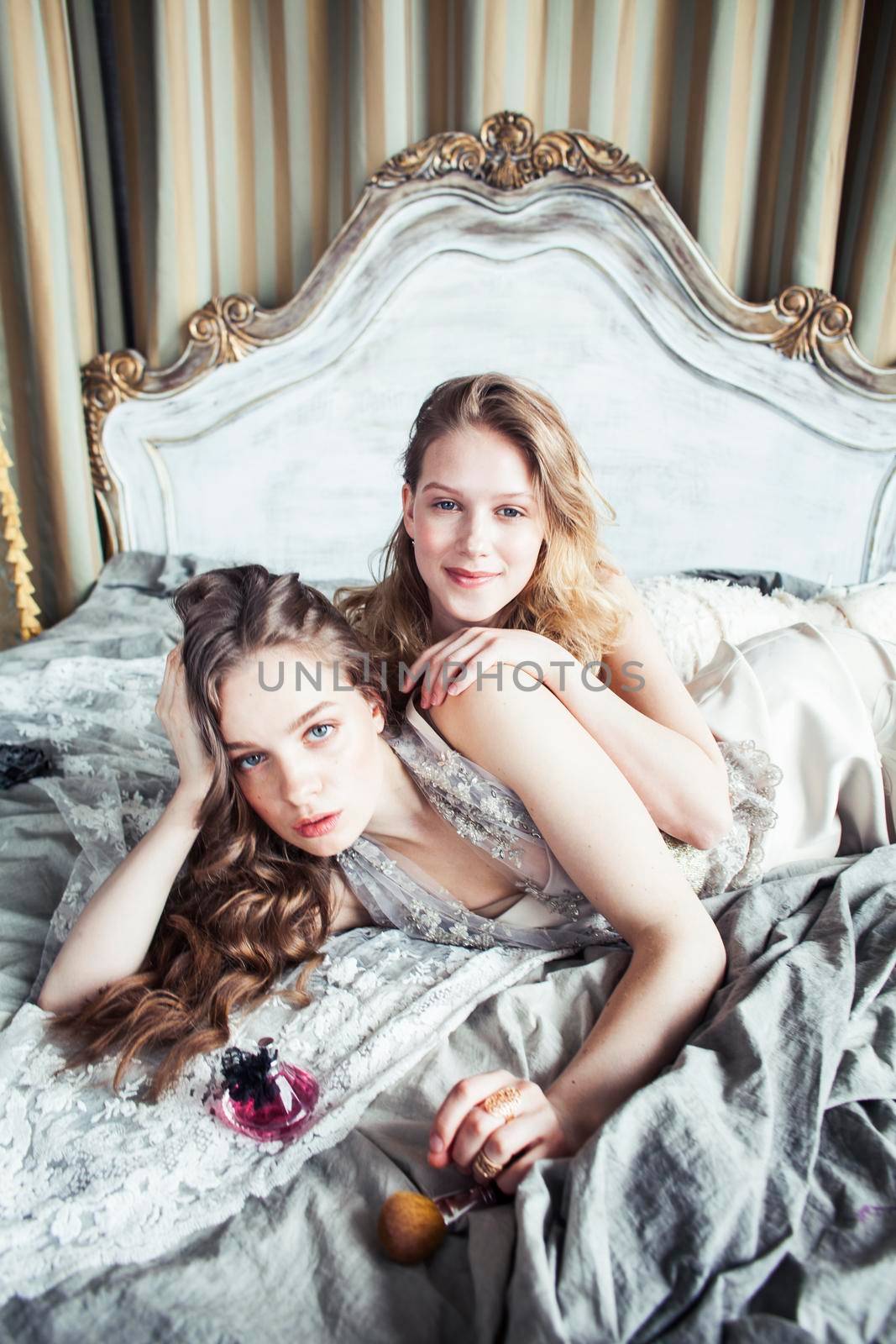 two pretty twin sister blond curly hairstyle girl in luxury house interior together, rich young people concept close up
