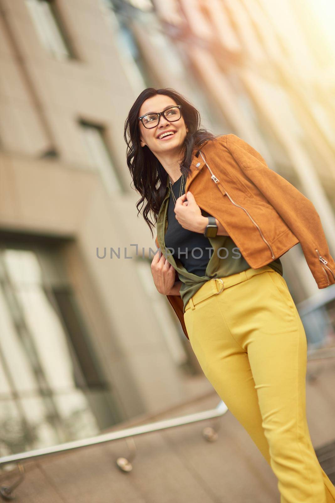 Perfect weather for walking. Full length of a young happy beautiful woman or business lady looking aside and smiling, walking city streets, vertical shot. People lifestyle concept