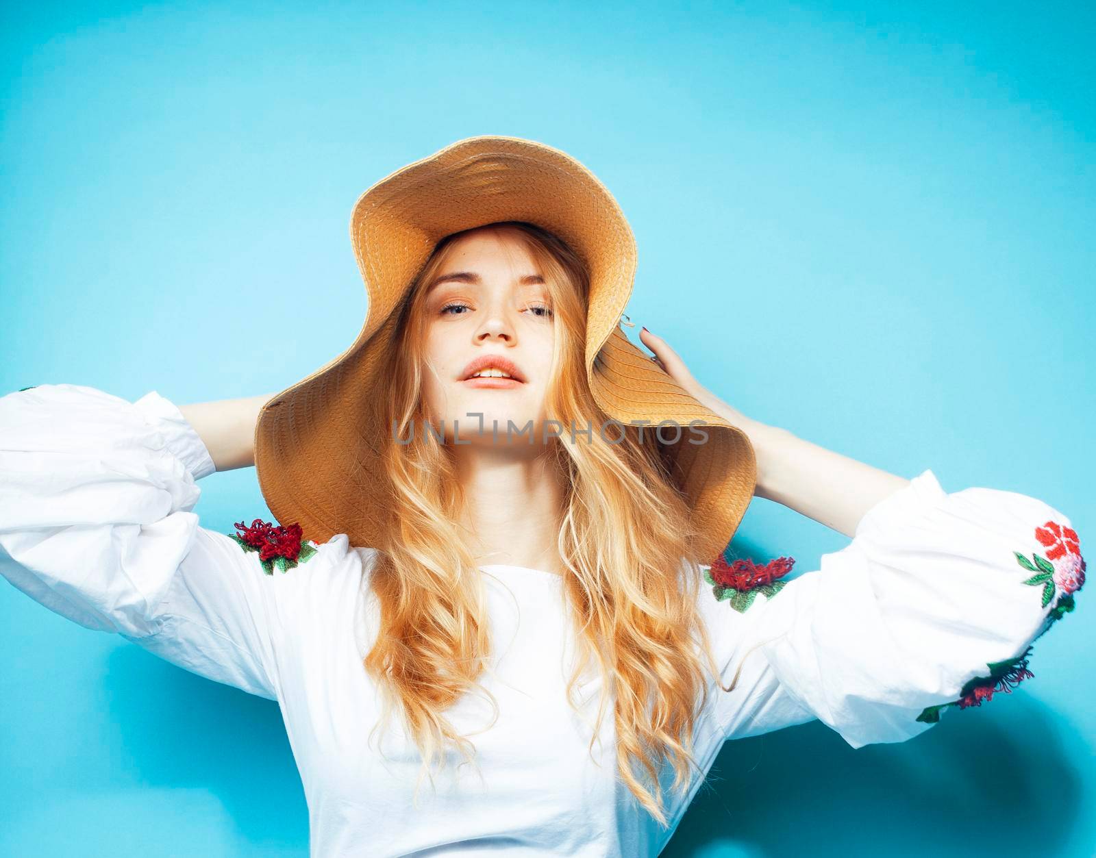 lifestyle people at summer vacation concept. young pretty smiling blond girl with long hair wearing lot of jewelry rings, sunglasses, hat posing cheerful on blue background close up