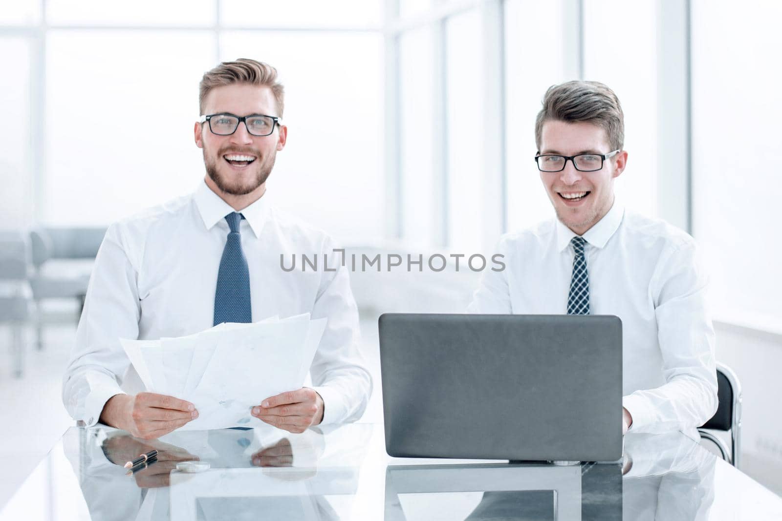 smiling colleagues sitting at the Desk. by asdf