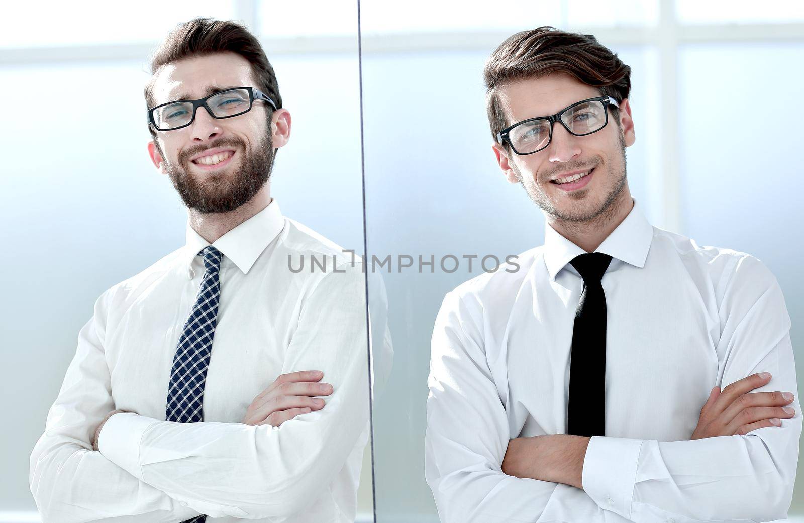 Two happy confident young businessmen standing with arms crossed in office.business concept