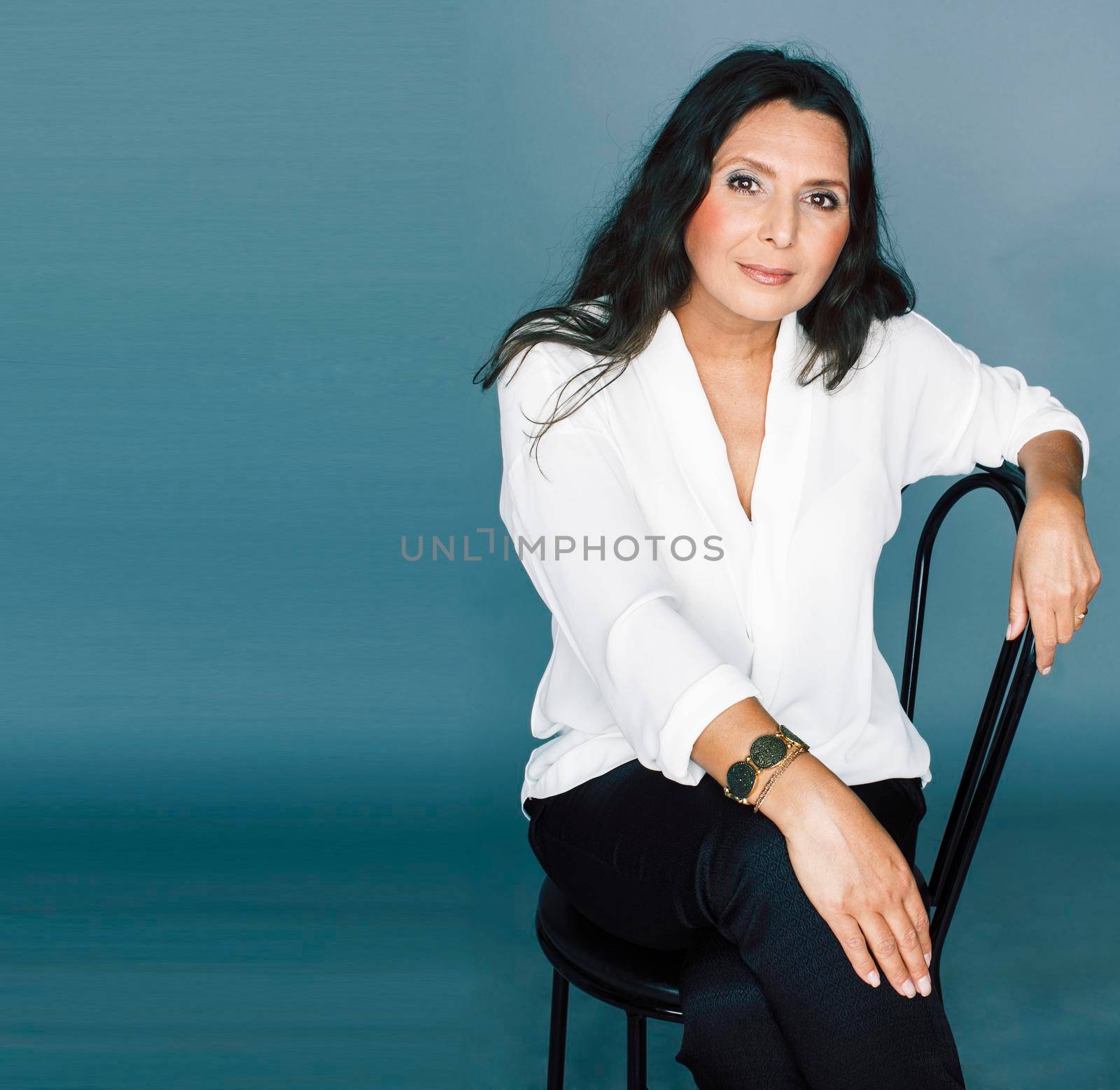 pretty brunette confident mature woman sitting on chair in studio, lifestyle people concept close up