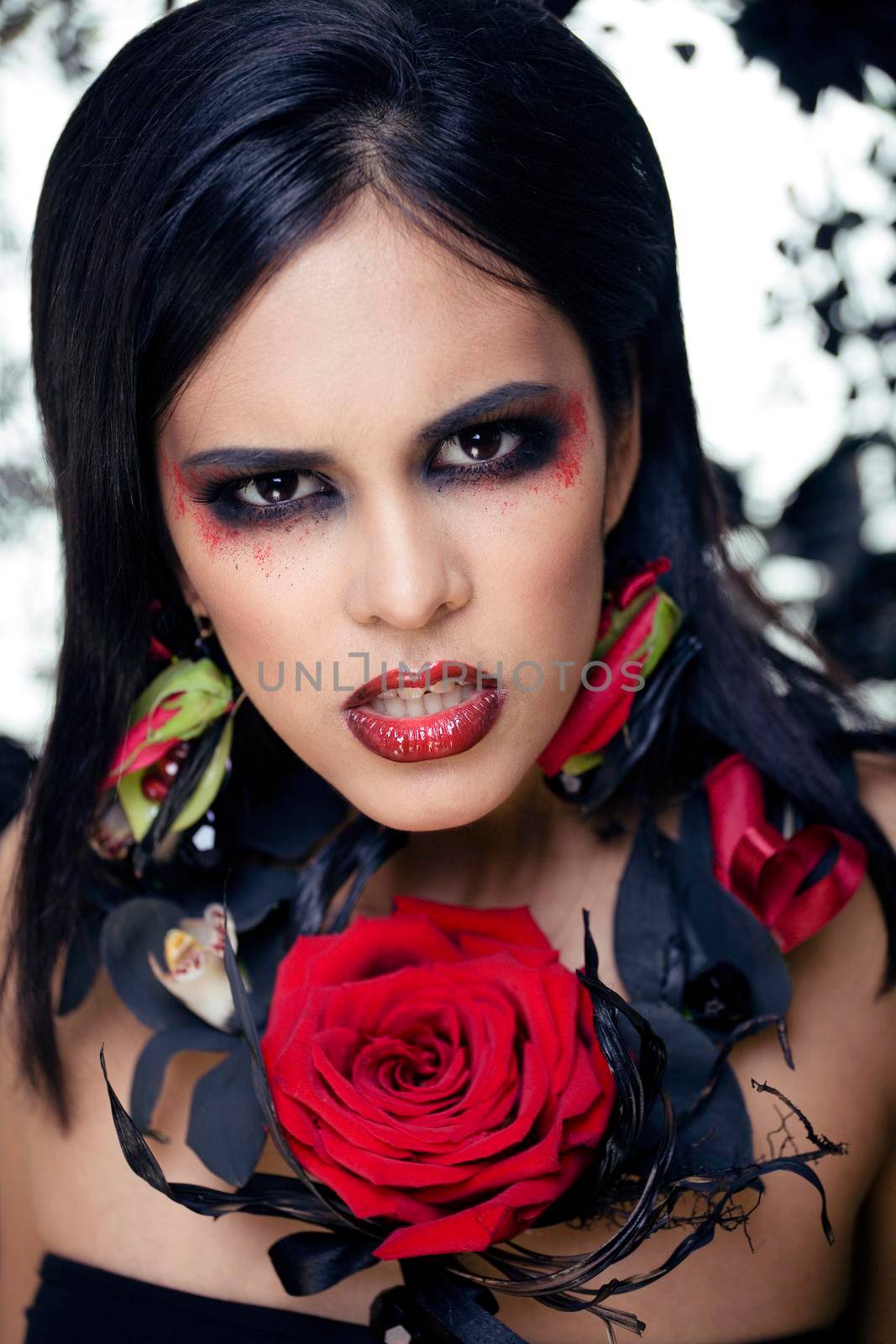 pretty brunette woman with rose jewelry, black and red, bright make up kike a vampire closeup red lips, halloween concept