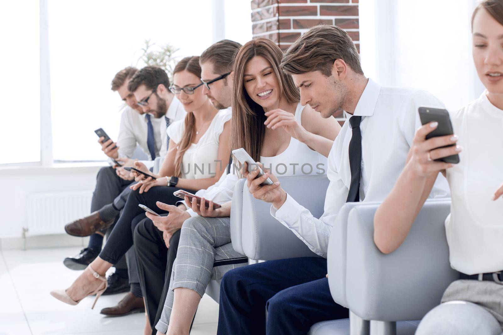 group of employees using their gadgets sitting in the office hallway .photo with copy space