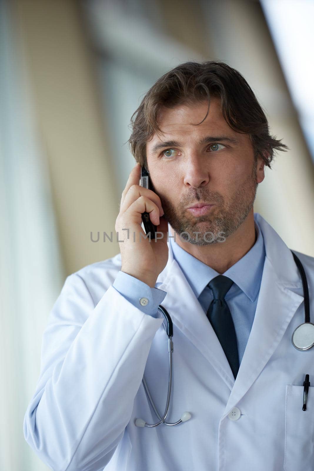 handsome doctor speaking on cellphone at modern hospital indoors