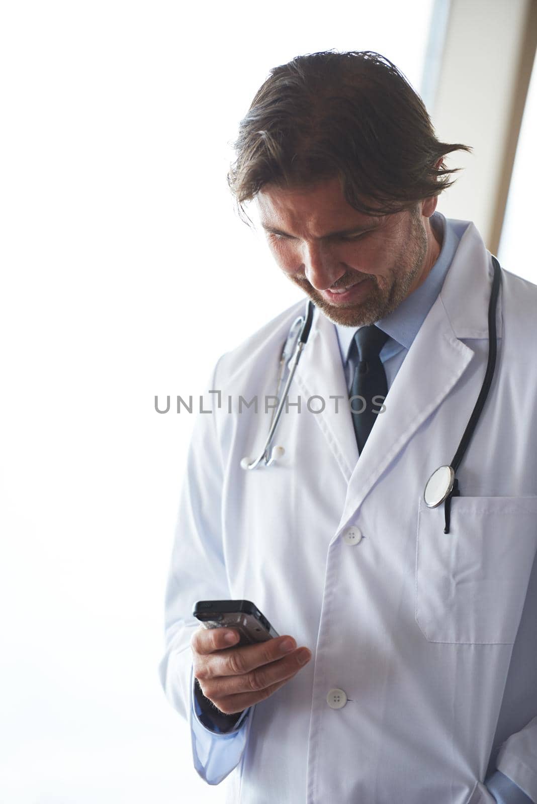 handsome doctor speaking on cellphone at modern hospital indoors