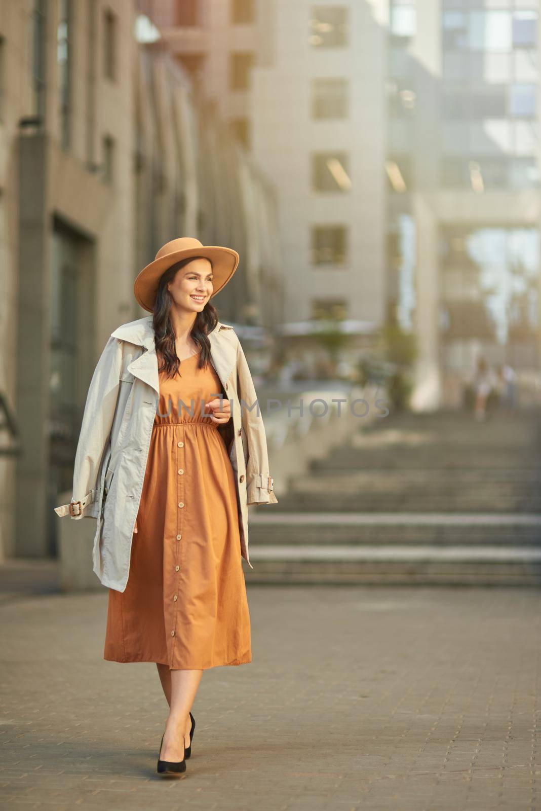 Full length of a young beautiful and stylish caucasian woman wearing long romantic dress and hat looking aside while walking outdoors by friendsstock