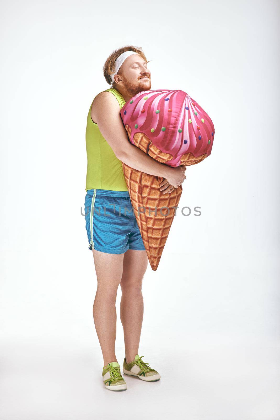 Funny picture of red haired, bearded, plump man on white background. Man holding a big ice cream