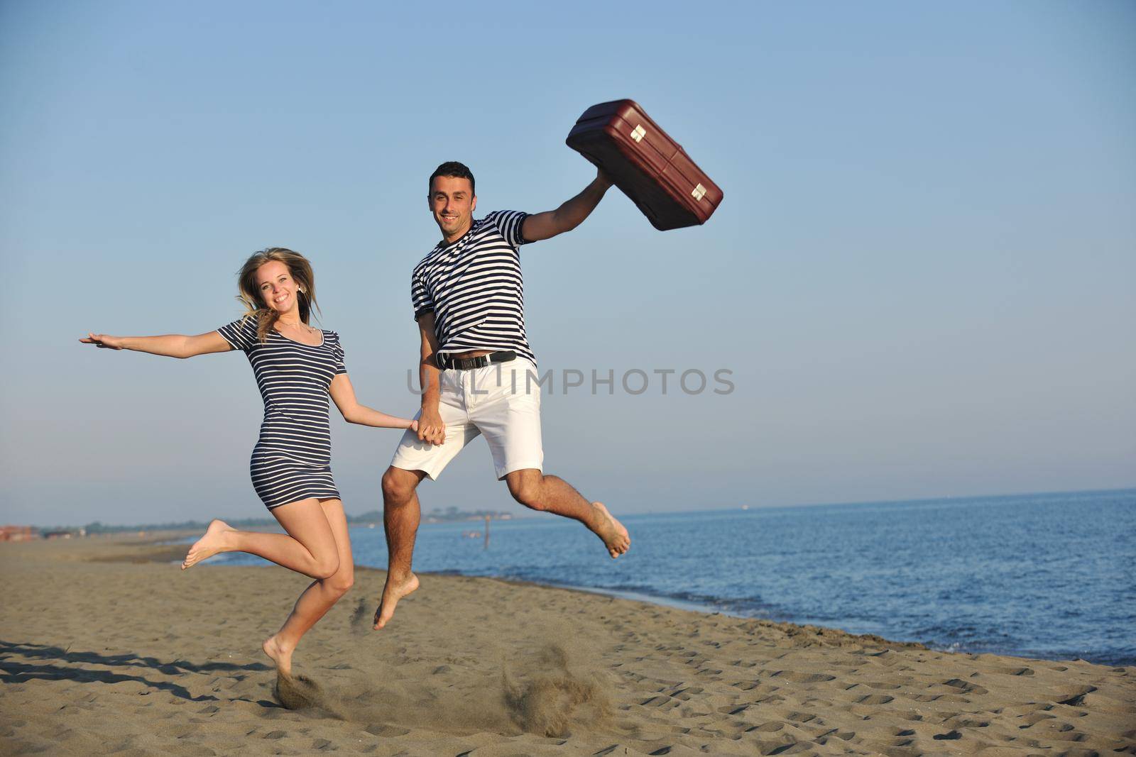 couple on beach with travel bag representing freedom and funy honeymoon concept