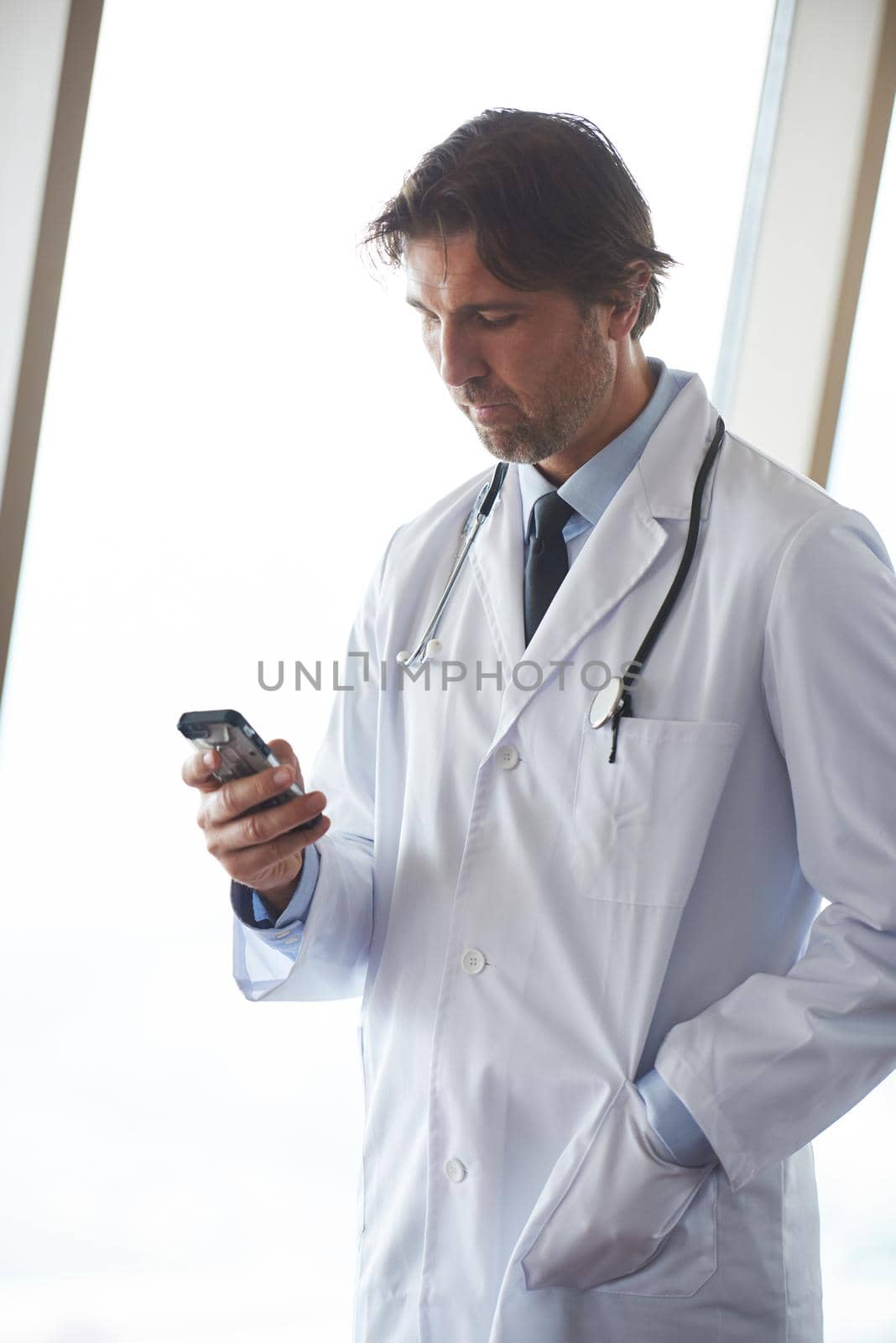 handsome doctor speaking on cellphone at modern hospital indoors