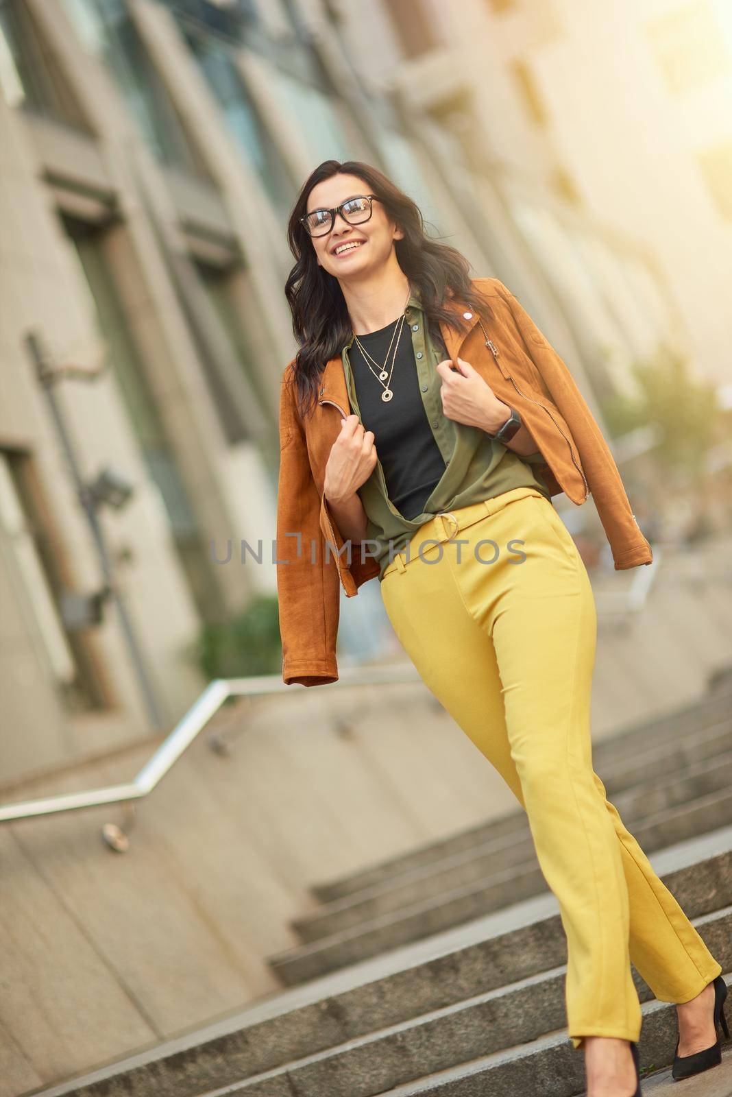 Enjoying nice day outdoors. Full length of a young beautiful and stylish caucasian woman or business lady walking city streets and smiling by friendsstock