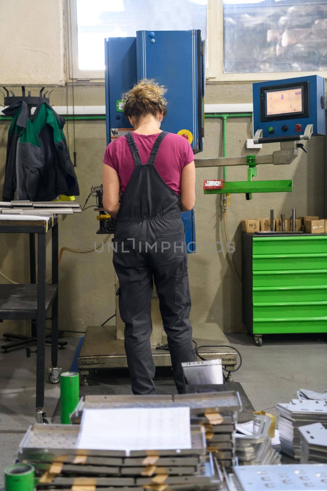 woman wearing mask due to coronavirus pandemic while working in modern metal industry and using drill by dotshock