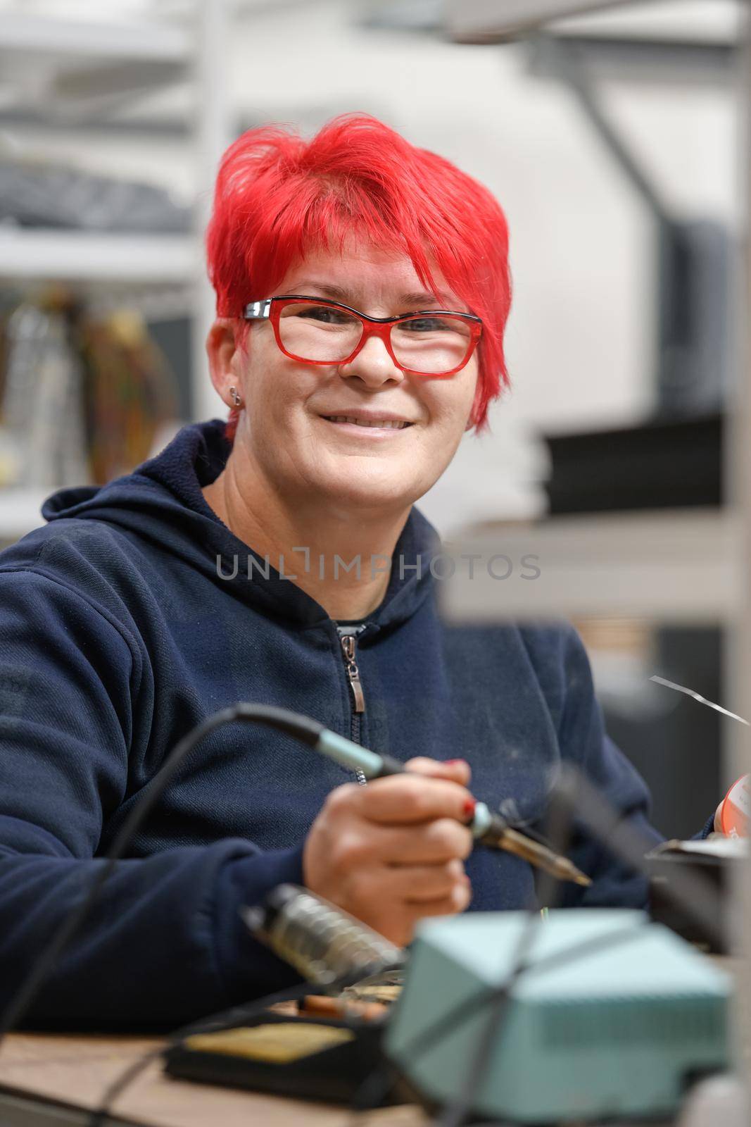 Industrial worker woman soldering cables of manufacturing equipment in a factory by dotshock