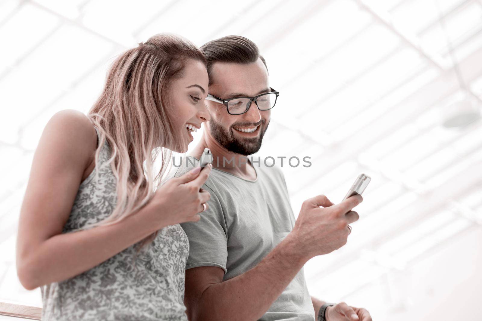 Laughing couple watching photos on smartphone by asdf